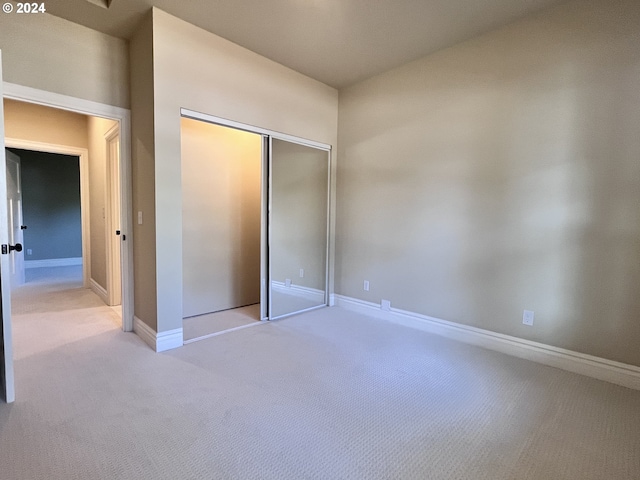 unfurnished bedroom with light colored carpet and a closet