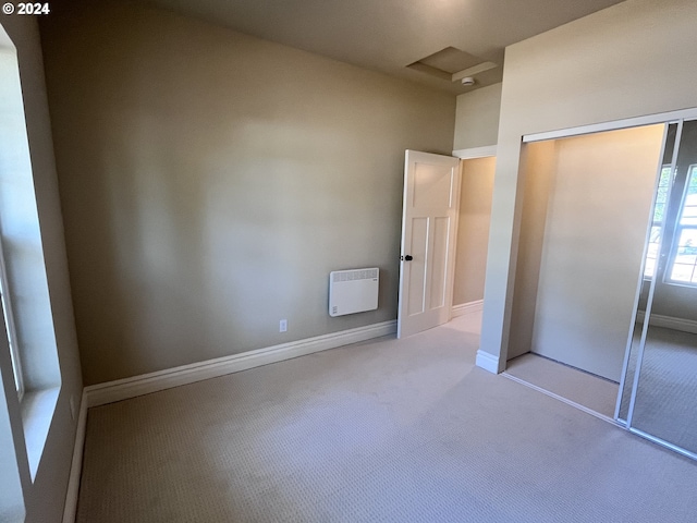 unfurnished bedroom featuring heating unit, light carpet, and a closet