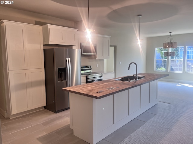 kitchen with sink, hanging light fixtures, an island with sink, white cabinets, and appliances with stainless steel finishes