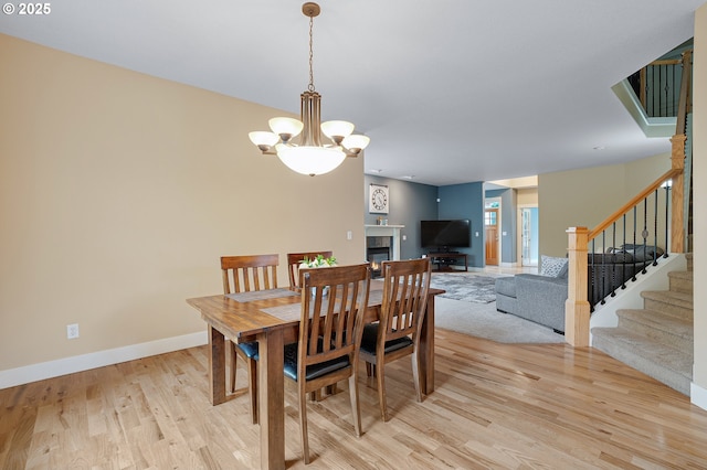 14386 NW Tripton Ct, Beaverton, OR 97006 - dining room with light wood-style flooring, stairway, a chandelier, and a tile fireplace