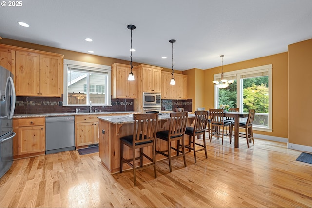 14386 NW Tripton Ct, Beaverton, OR 97006 - kitchen featuring stainless steel appliances, light brown cabinets, light wood finished floors, a chandelier, and decorative backsplash