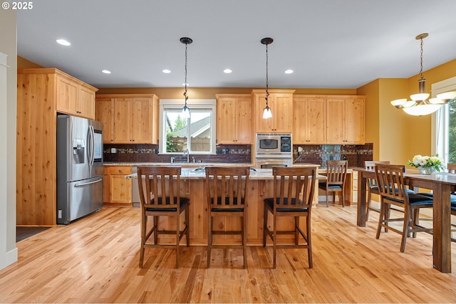 14386 NW Tripton Ct, Beaverton, OR 97006 - kitchen with stainless steel appliances, light brown cabinets, light wood-type flooring, tasteful backsplash, and a chandelier