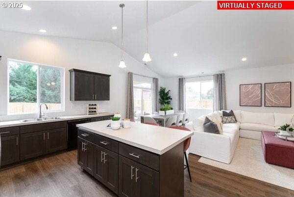 kitchen featuring lofted ceiling, open floor plan, dark wood-style flooring, a center island, and a sink