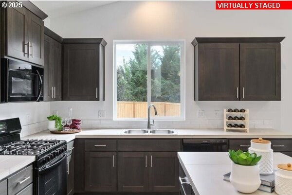 kitchen with dark brown cabinetry, light countertops, a sink, and black appliances