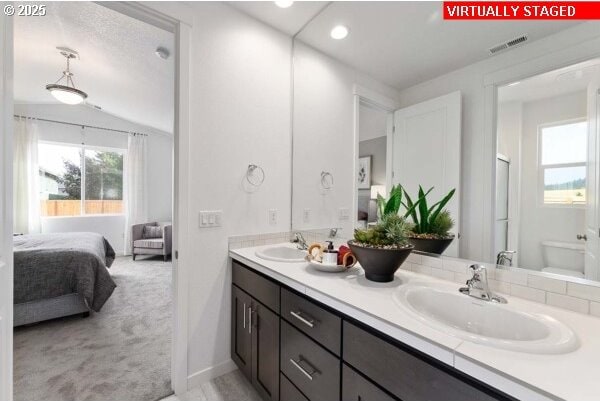 bathroom featuring double vanity, ensuite bath, a sink, and visible vents