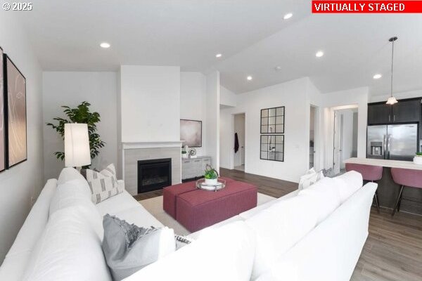 living area featuring lofted ceiling, recessed lighting, a fireplace, and light wood-style floors