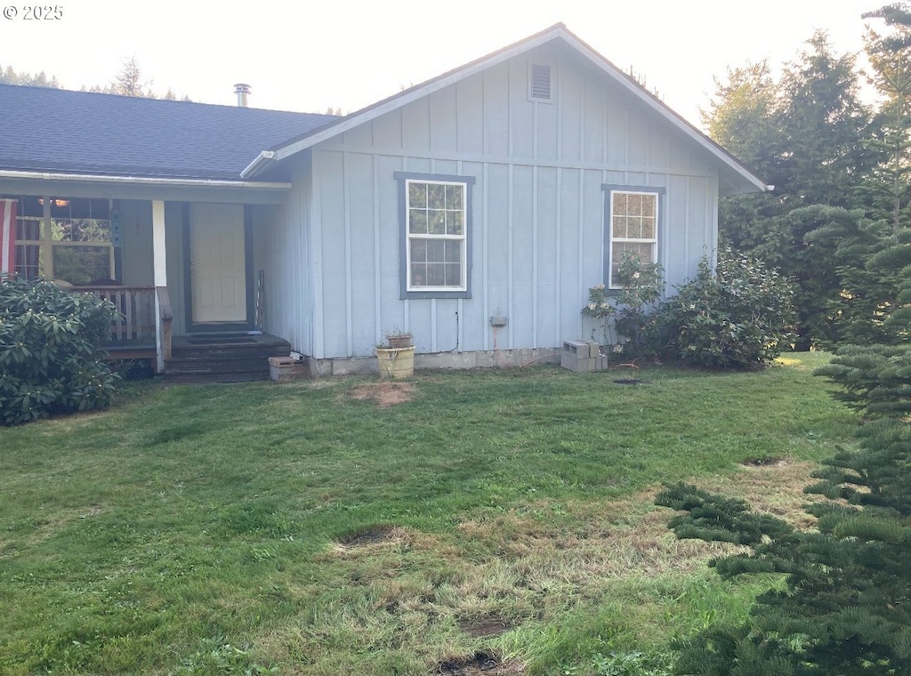 single story home featuring board and batten siding, a front yard, and covered porch
