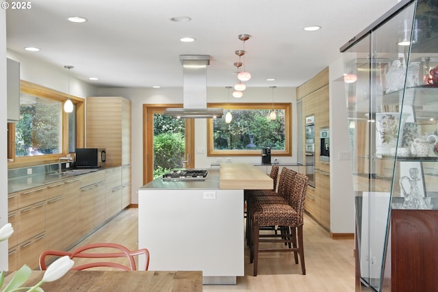 kitchen featuring stainless steel gas stovetop, modern cabinets, light wood-type flooring, and island exhaust hood