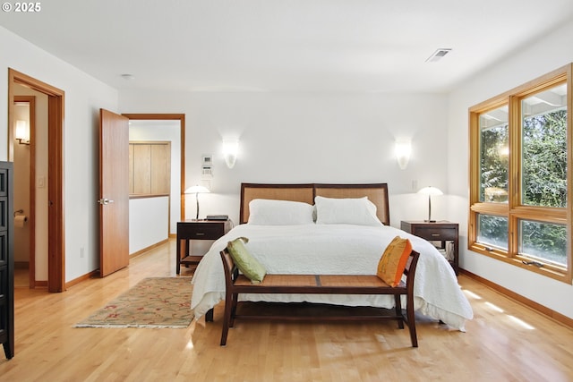 bedroom featuring baseboards, light wood-type flooring, and visible vents