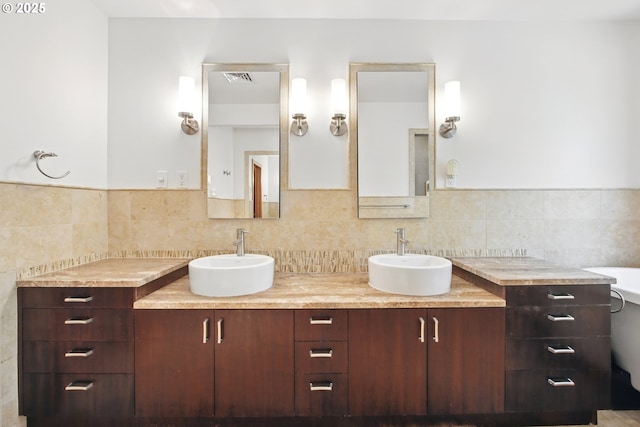 bathroom featuring backsplash, double vanity, visible vents, and a sink