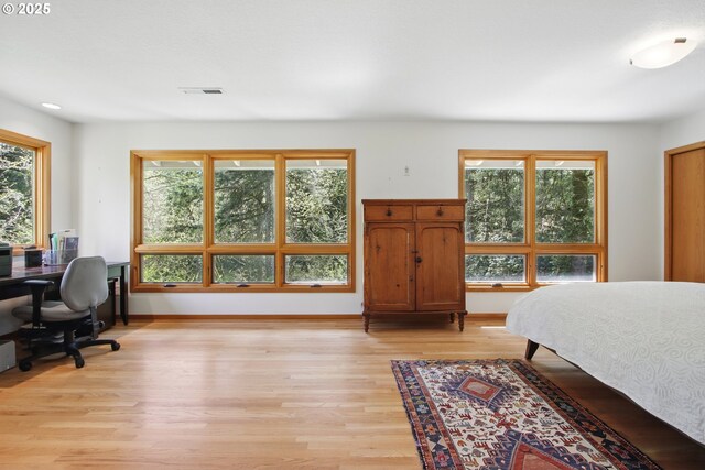 bedroom with baseboards, light wood finished floors, and visible vents