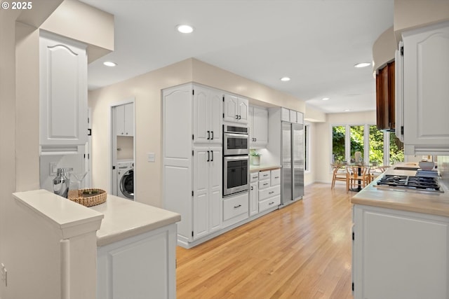 2395 SW Timberline Dr, Portland, OR 97225 - kitchen with appliances with stainless steel finishes, washer / clothes dryer, light wood-style flooring, white cabinetry, and light countertops