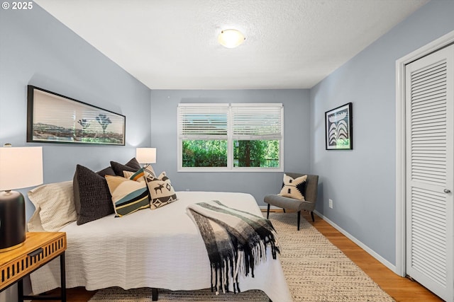 2395 SW Timberline Dr, Portland, OR 97225 - bedroom with wood finished floors, a closet, baseboards, and a textured ceiling