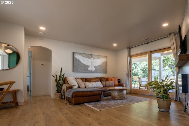 living room featuring visible vents, baseboards, recessed lighting, wood finished floors, and arched walkways