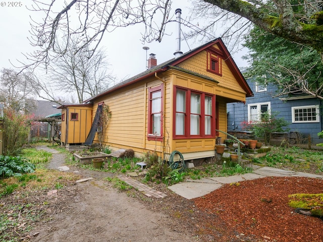 view of side of home featuring a chimney and fence