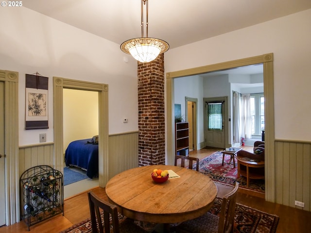 dining room with a wainscoted wall, wooden walls, and wood finished floors