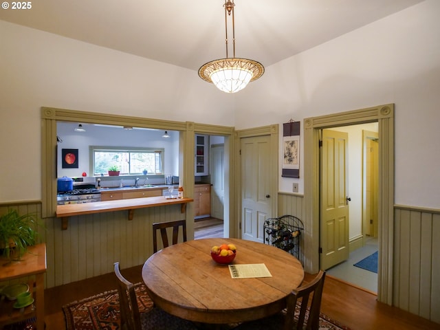 dining space with wood finished floors and a wainscoted wall