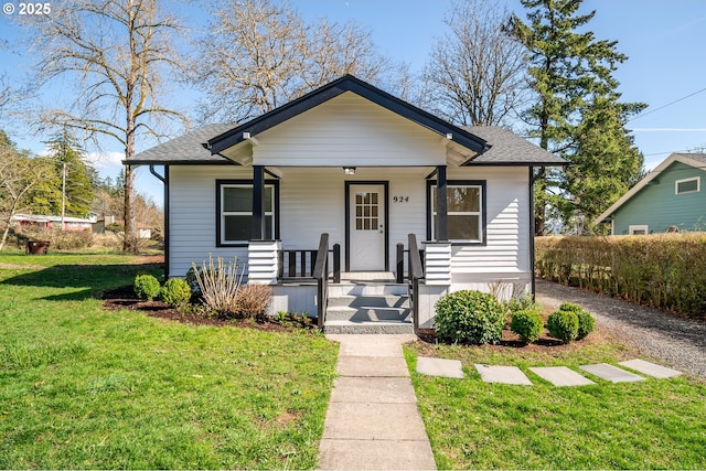 bungalow featuring a porch, a front yard, and a shingled roof