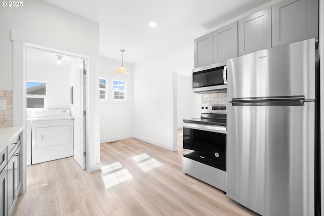 kitchen featuring independent washer and dryer, tasteful backsplash, light wood-style floors, appliances with stainless steel finishes, and light countertops