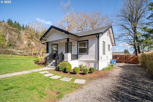 bungalow with a front lawn, covered porch, driveway, and fence