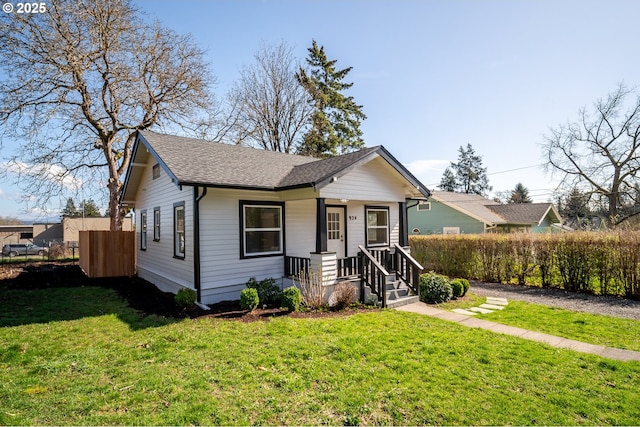 bungalow with a shingled roof, a front yard, and fence