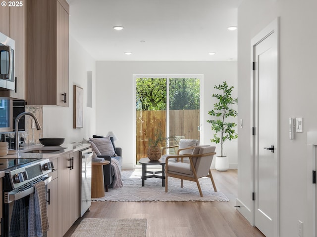 kitchen featuring stainless steel appliances, recessed lighting, light wood-type flooring, and a sink