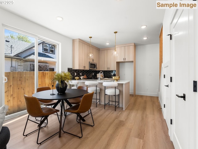 dining space with light wood finished floors, baseboards, and recessed lighting