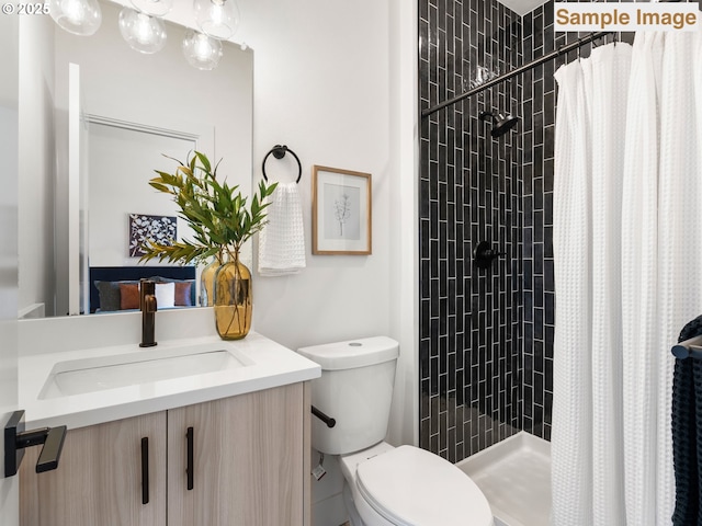 bathroom featuring vanity, a tile shower, and toilet