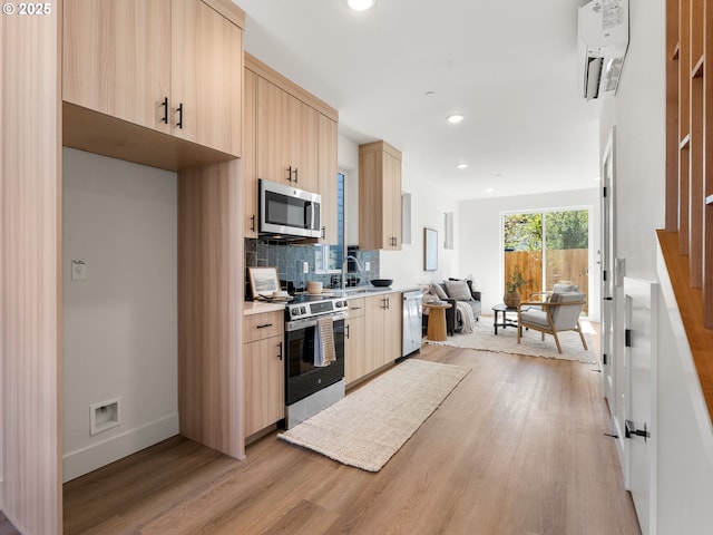 kitchen with light wood-style flooring, light brown cabinetry, light countertops, stainless steel appliances, and decorative backsplash