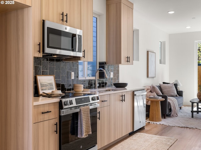 kitchen featuring tasteful backsplash, light wood-style floors, light brown cabinets, and stainless steel appliances