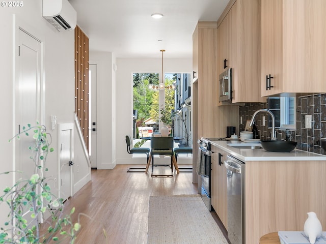 kitchen featuring light wood-type flooring, appliances with stainless steel finishes, light countertops, a wall mounted air conditioner, and backsplash