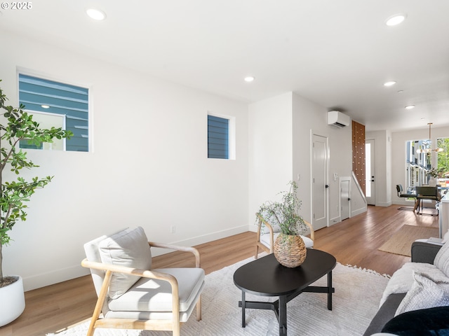 living area featuring baseboards, recessed lighting, an inviting chandelier, and a wall mounted air conditioner
