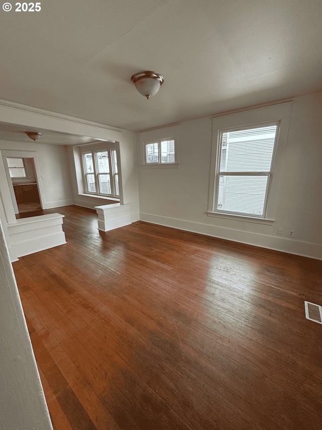 unfurnished living room featuring baseboards, visible vents, and hardwood / wood-style floors