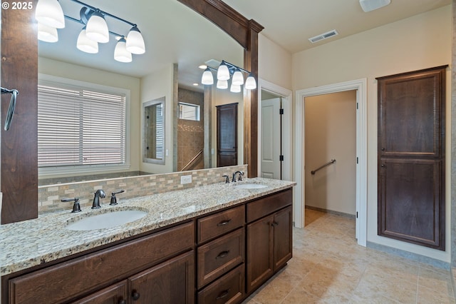 full bath featuring backsplash, tile patterned flooring, double vanity, and a shower