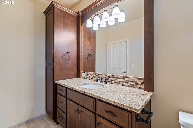 bathroom featuring vanity, decorative backsplash, toilet, baseboards, and tile patterned floors