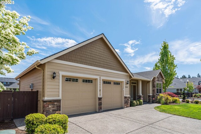 craftsman house with stone siding, concrete driveway, fence, and a garage