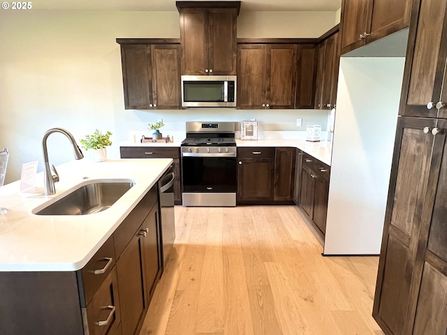 947 Medina Ave, Sutherlin, OR 97479 - kitchen with dark brown cabinetry, light wood-style flooring, light countertops, stainless steel appliances, and a sink