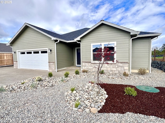 947 Medina Ave, Sutherlin, OR 97479 - ranch-style house with fence, stone siding, an attached garage, a shingled roof, and driveway