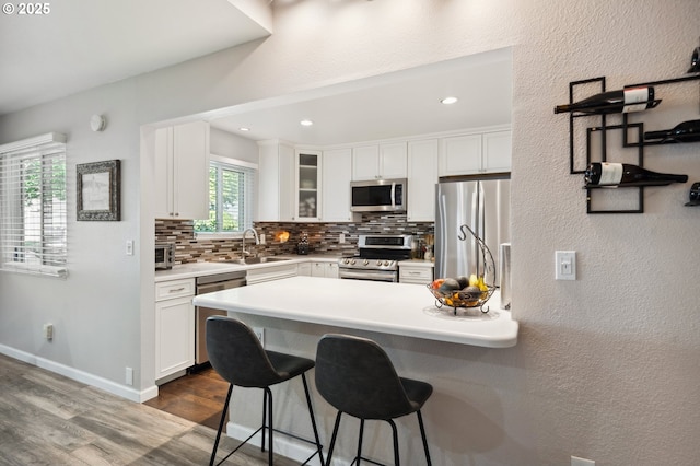 17622 NW Rolling Hill Ln, Beaverton, OR 97006 - kitchen with stainless steel appliances, a breakfast bar, dark wood finished floors, tasteful backsplash, and white cabinets