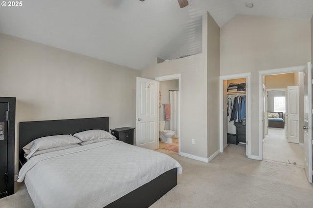 bedroom with light carpet, baseboards, a closet, a walk in closet, and ensuite bath