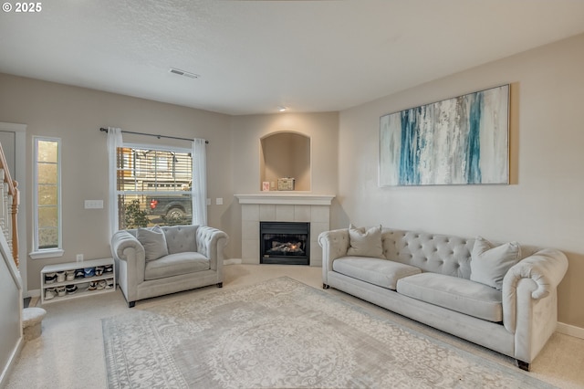 living room with stairs, a tile fireplace, carpet flooring, and baseboards