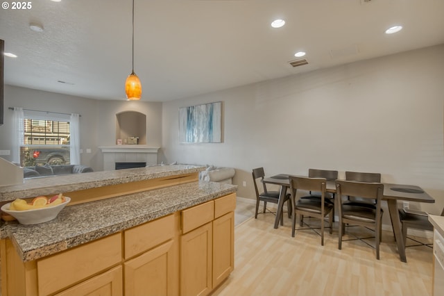 kitchen with light wood-style floors, open floor plan, a fireplace, and light brown cabinetry