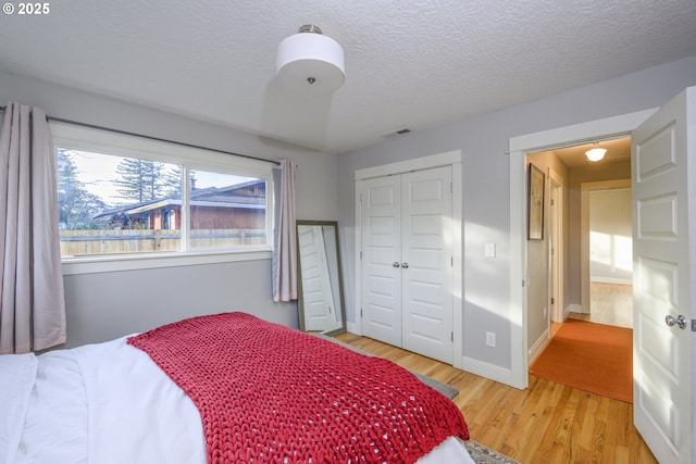 bedroom featuring a textured ceiling, light hardwood / wood-style floors, and a closet