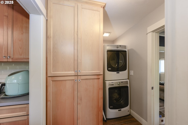 laundry area featuring cabinets and stacked washing maching and dryer