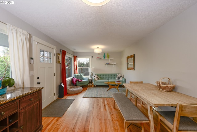 dining area with a healthy amount of sunlight, light hardwood / wood-style floors, and a textured ceiling