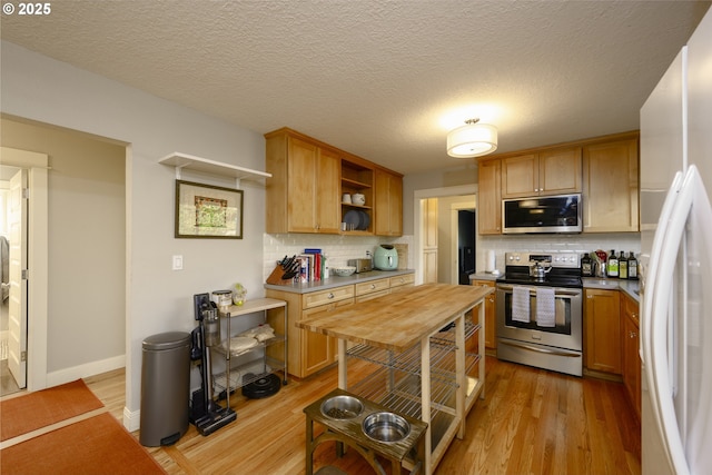 kitchen with appliances with stainless steel finishes, a textured ceiling, backsplash, and light wood-type flooring