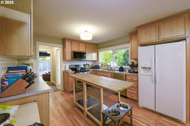 kitchen with sink, light hardwood / wood-style flooring, appliances with stainless steel finishes, backsplash, and a textured ceiling