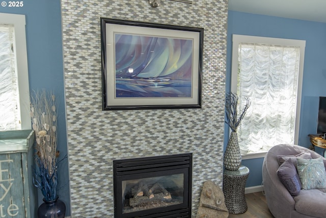 interior space with a tiled fireplace and wood finished floors