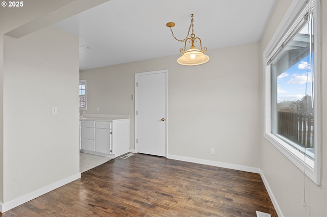 spare room with dark hardwood / wood-style floors and a notable chandelier