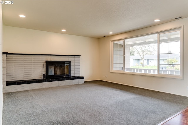 unfurnished living room with carpet flooring, recessed lighting, a fireplace, and visible vents